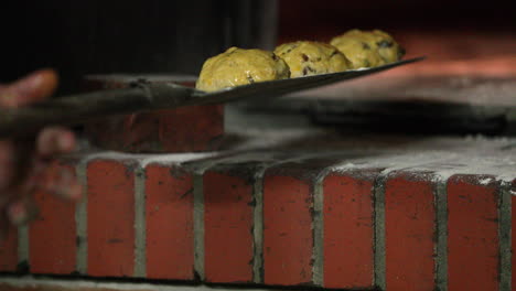 baker putting raisin bread dough brushed with egg wash on a baking peel - close up