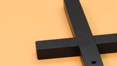 wooden christian cross over orange surface, close up view