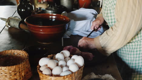 A-Woman-In-Traditional-Dress-Of-American-Pioneer-Immigrants-Prepares-Food-Cuts-Meat-With-A-Knife