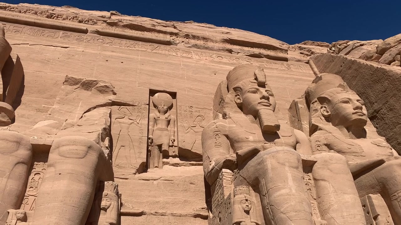 Abú Simbel v Egyptě. Kolosální sochy lemují vchod do tohoto starověkého chrámu postaveného Ramessem II. Den, panorámování doleva.