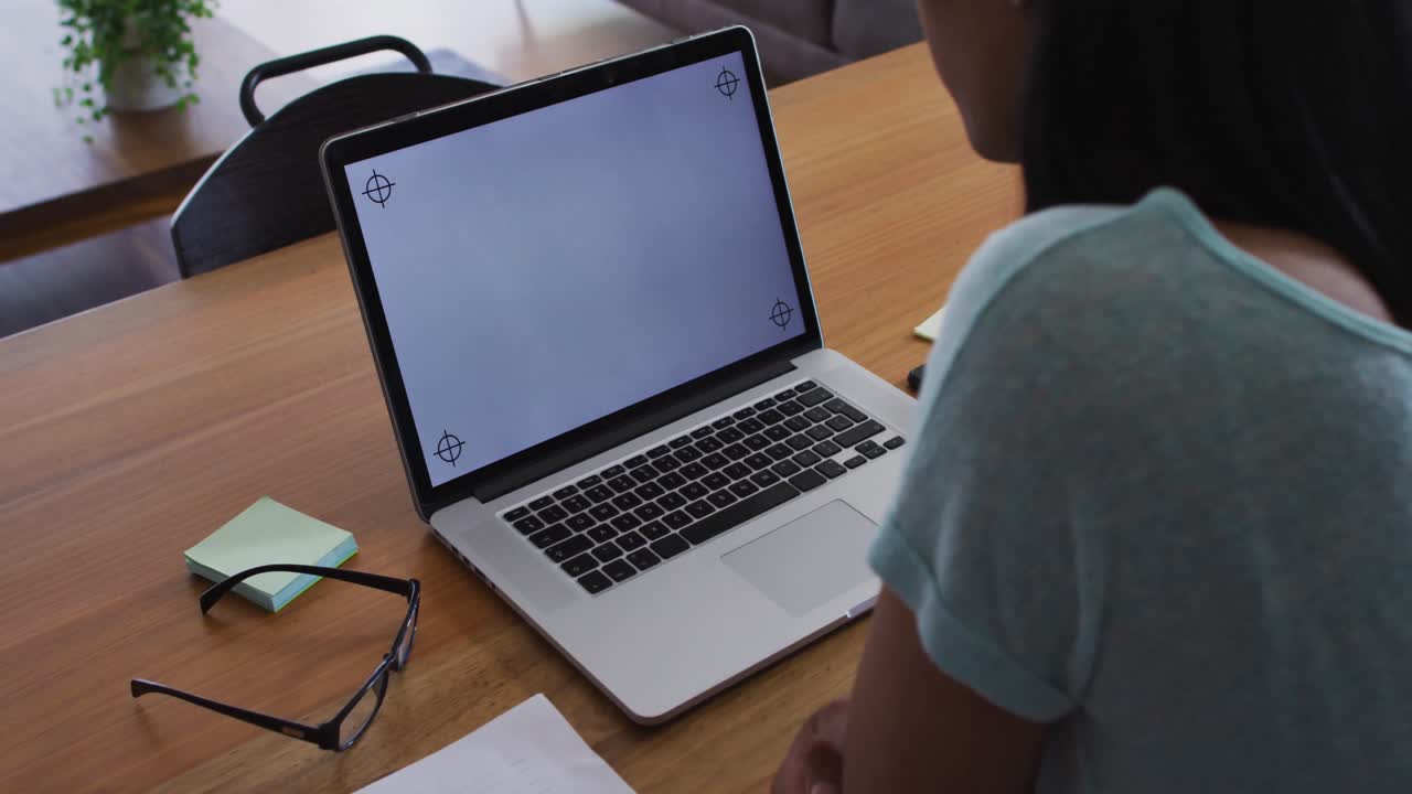 Mixed race gender fluid person sitting at desk working from home using a laptop