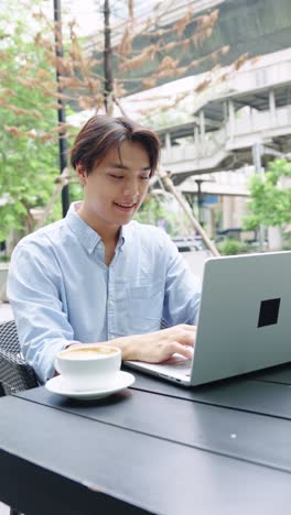 Man working on laptop at outdoor cafe