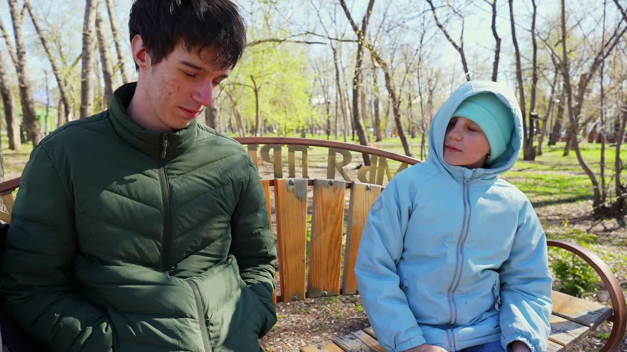 公園のベンチに一緒に座る若い男性と子供
