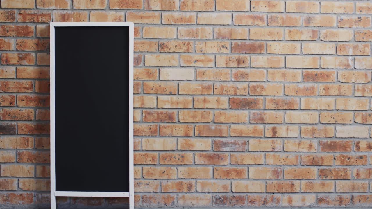 Video of blackboard sign on white stand with copy space on brick wall background