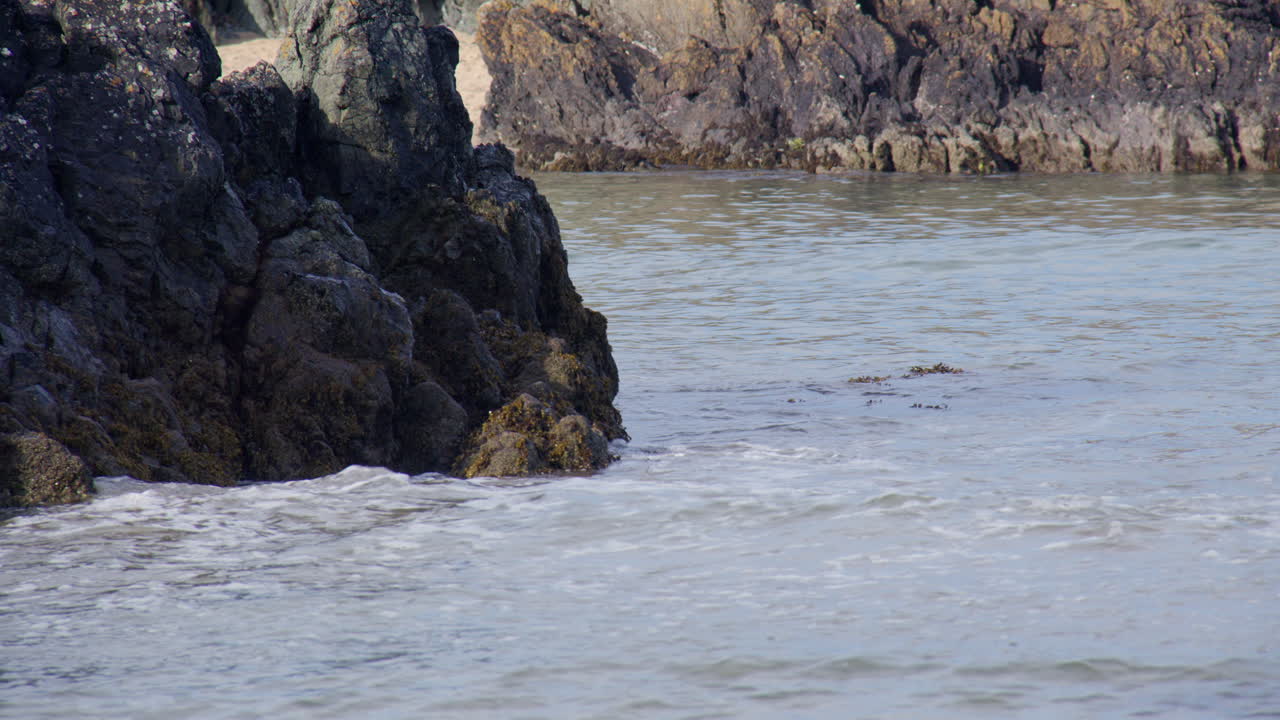 Shot of small Waves breaking over rocks at Llanddwyn beach and at the Newborough National Nature Reserve