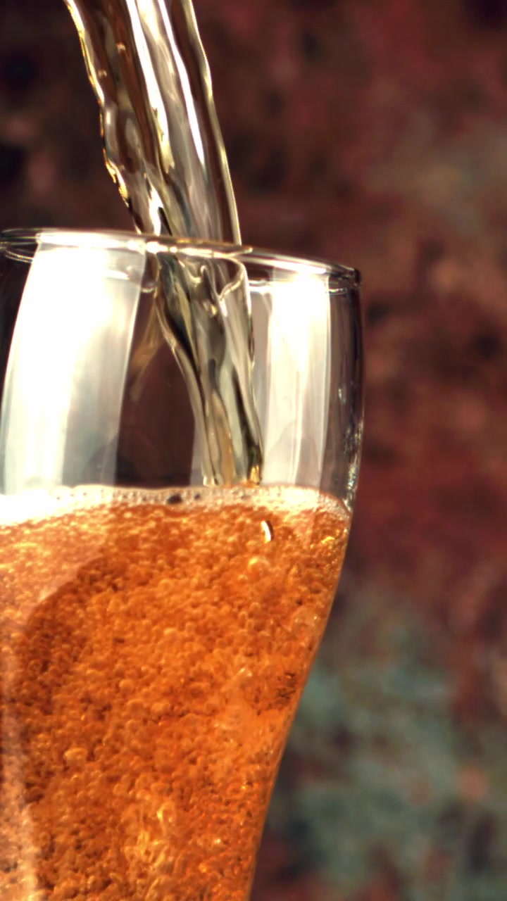 Primo piano di birra dorata che si versa in un bicchiere con bollicine