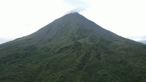 vista aérea en movimiento, vista panorámica del volcán arena en costa rica, nubes en la punta del volcán en el fondo
