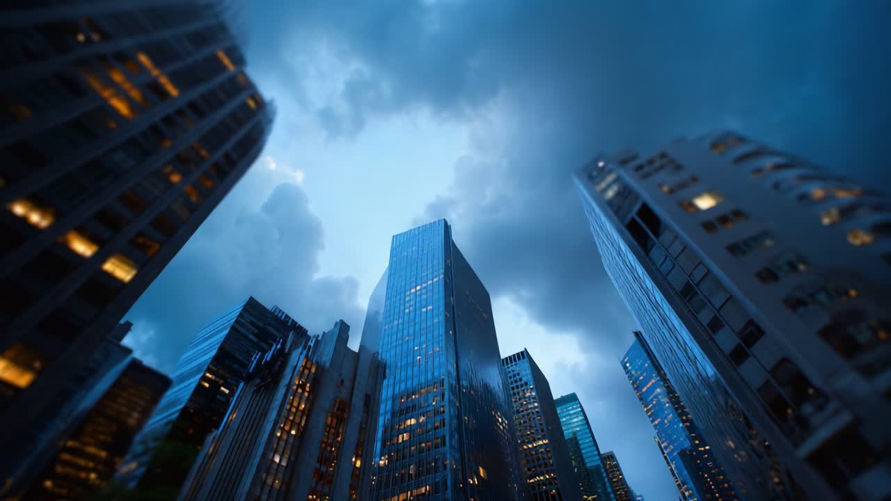 Grattacieli che si ergono verso un cielo che si fa scuro: una scena urbana mozzafiato catturata tra il giorno e la notte, tra nuvole avvolgenti e finestre illuminate