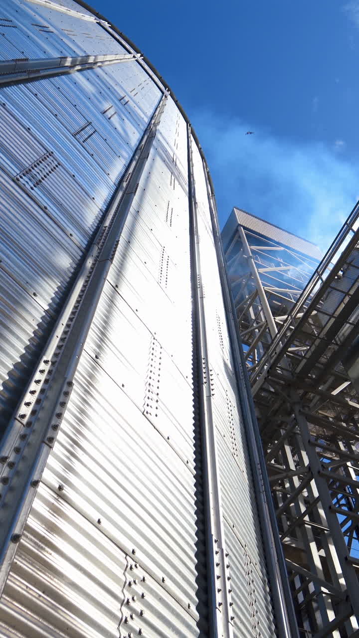 Modern complex for agribusiness. Large storage container. Industrial equipment for drying grains. Metal construction for storing crop. Industry outdoors. Vertical video