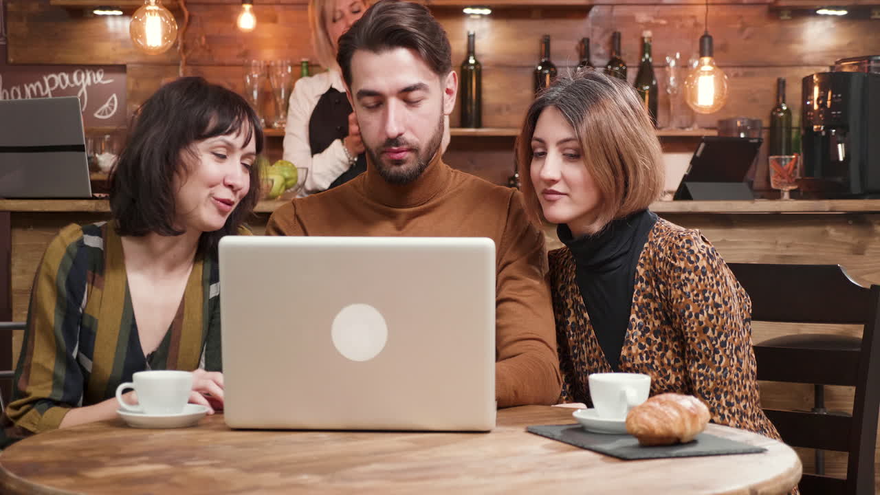 Grupo de personas en una cafetería mirando un portátil