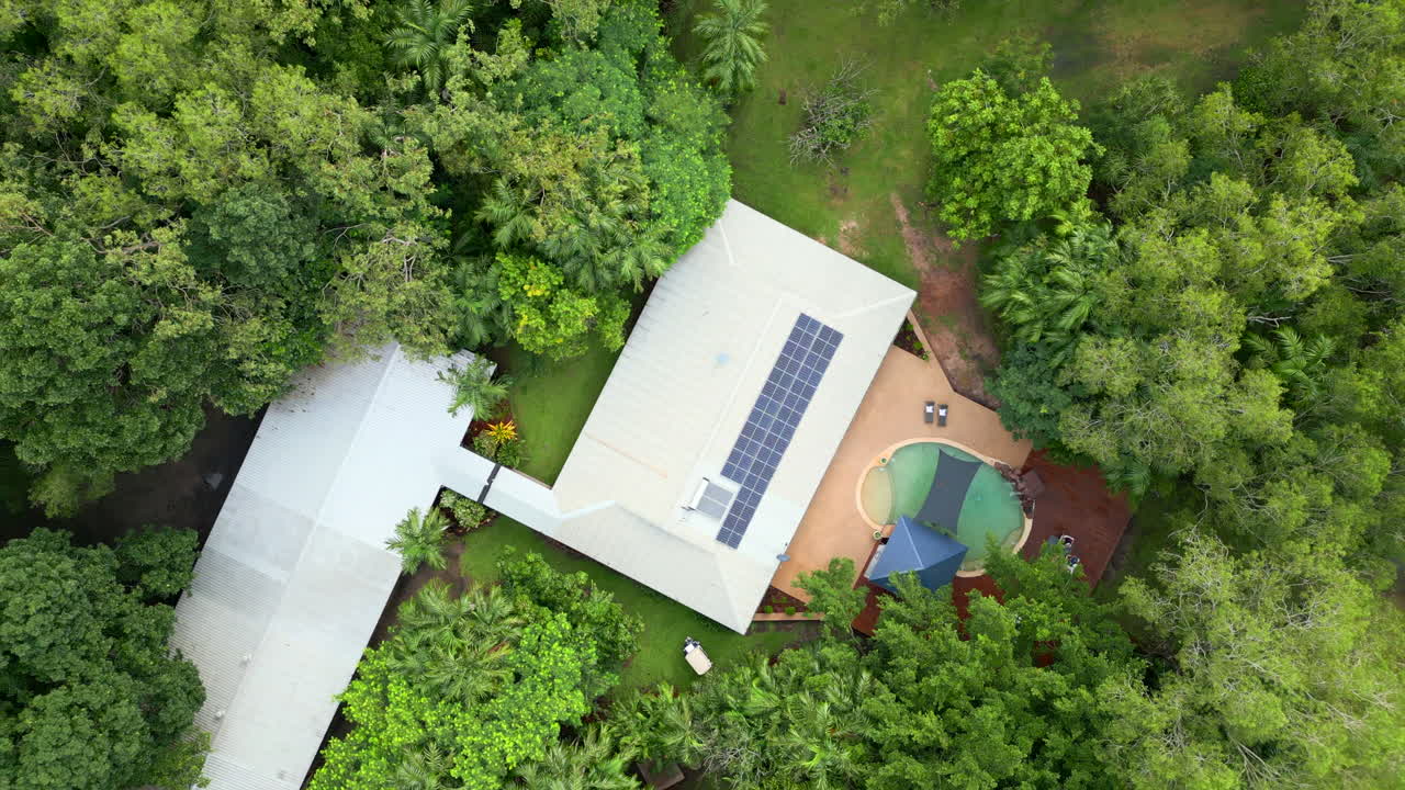 Ripresa Aerea con Drone in Discesa Rotante dall'Alto su una Proprietà Tropicale con Piscina e Pannelli Solari in una Foresta Temperata Tropicale.