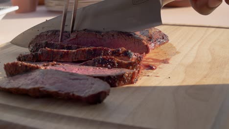 person slicing cooked meat on a cutting board