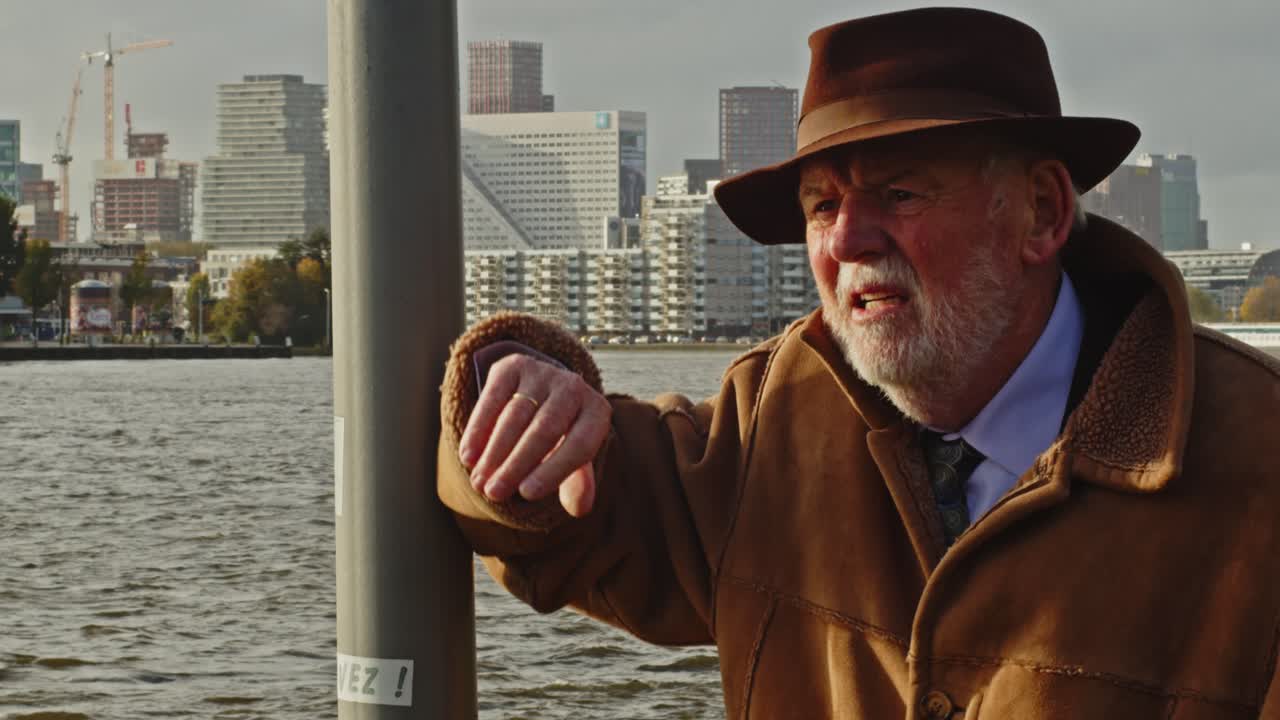 레트로 의상 을 입은 노인 이 램프 기둥 에 기대어 숨 을 쉬고 있다