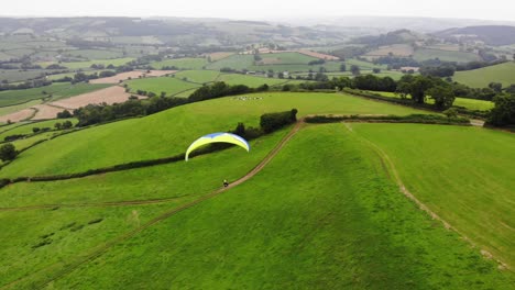 toma de paralaje de un parapente volando sobre la campiña de east devon, inglaterra