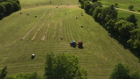 tractor with baler working over green hay field in oronoco, minnesota, usa - aerial shot