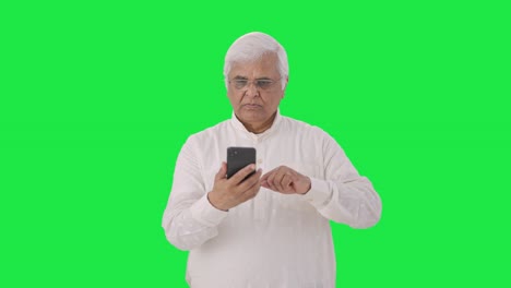 Serious-Indian-old-man-scrolling-through-phone-Green-screen