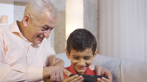 Feliz-Padre-E-Hijo-Mirando-El-Teléfono.-Niño-Confundido.