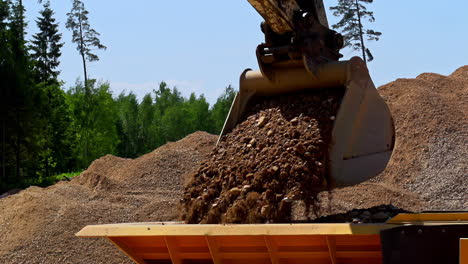 slow motion shot of excavator shovel arm pick rocks and unloading in container