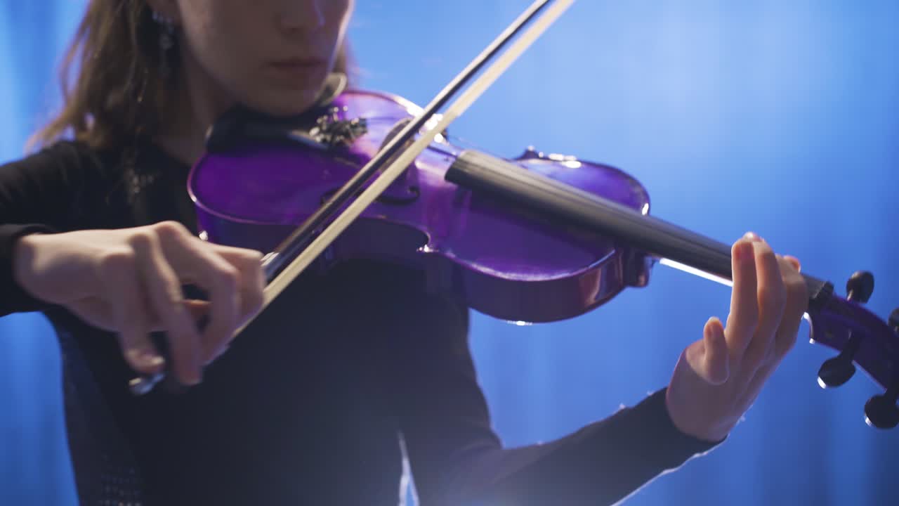 primer plano de una joven músico que toca el violín en el escenario y su violín.