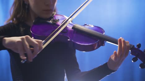 Close-up-of-young-female-musician-playing-violin-on-stage-and-her-violin.