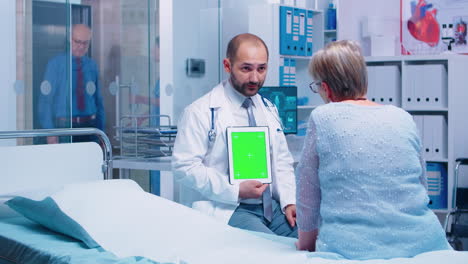 médico con tableta de pantalla verde frente al paciente de edad avanzada