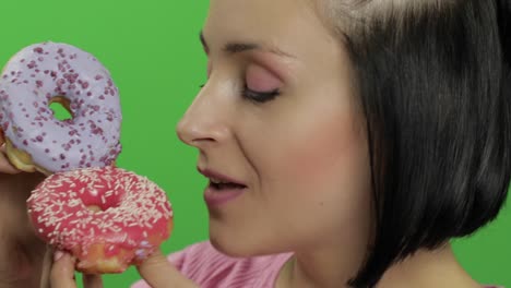 woman eating a pink and a purple donut