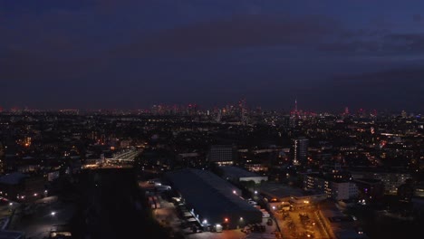 aerial slider drone shot towards central london skyline over residential buildings at night