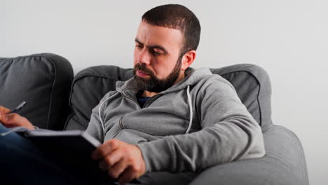 Sitzender-Mann-Auf-Der-Couch,-Der-Zu-Hause-Notizen-Macht