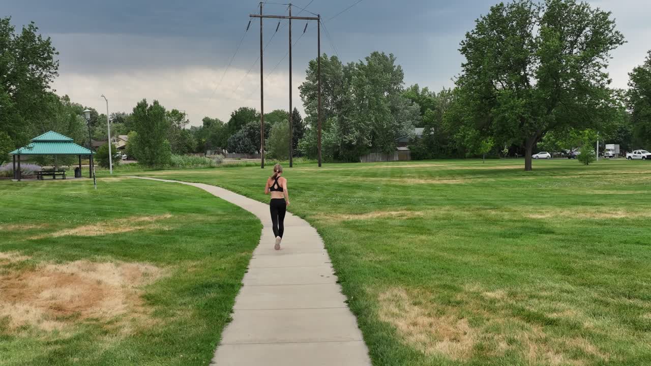 Fit and healthy practices. A woman does cardio while running on a stormy day through a city park