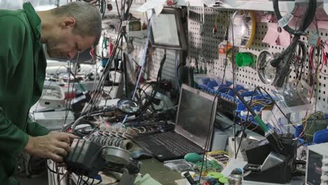 tienda de reparación de equipos electrónicos. el técnico ingeniero soldada la placa de circuitos impresos de un dispositivo electrónico bajo un microscopio.
