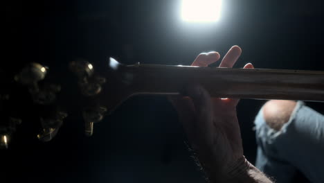 rear view of man playing guitar with strong background lighting