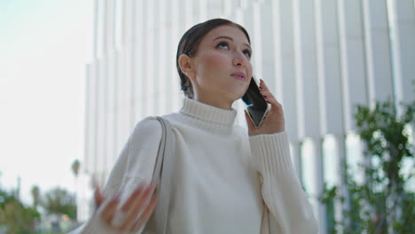 Side-view-woman-calling-phone-walking-city-street-closeup.-Girl-talking-mobile.