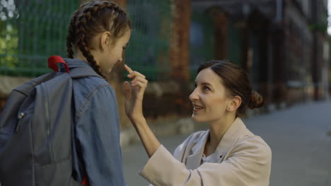 mother saying goodbye to her daughter at school