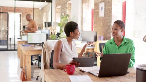 happy african american colleagues using tablet and discussing work in office, slow motion
