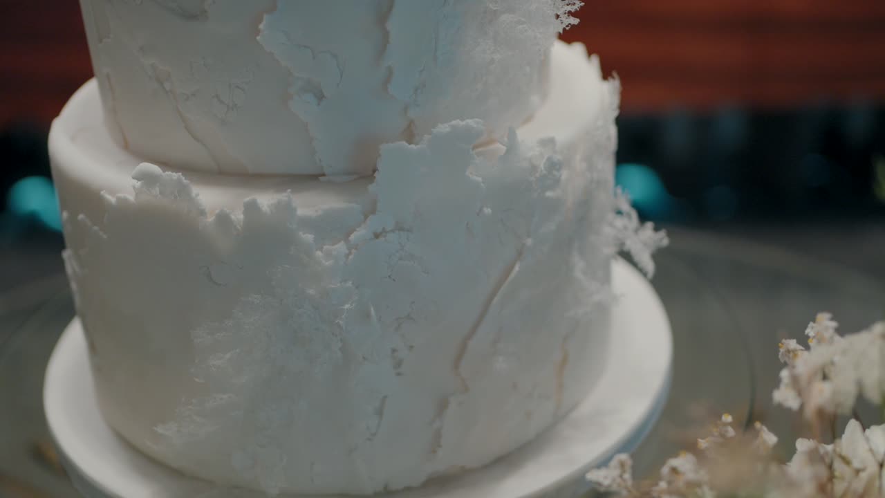 primer plano detallado de un pastel de bodas de niveles blancos con una superficie texturizada, elegantemente exhibido