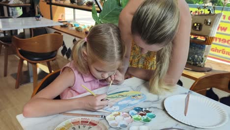 mother and daughter painting pottery