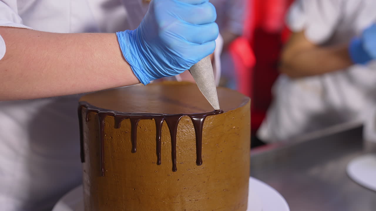 Decoration of cake with liquid chocolate. Melted chocolate flowing down from cake. Close up.