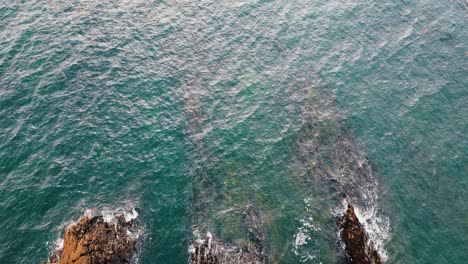 top aerial drone view of ocean waves crash against rocks in brittany, france bretagne