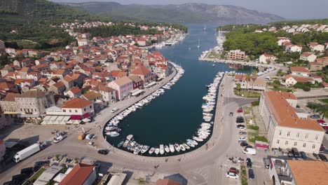 aerial: stari grad marina, hvar island, croatia: boats lining turquoise bay amid historic architecture