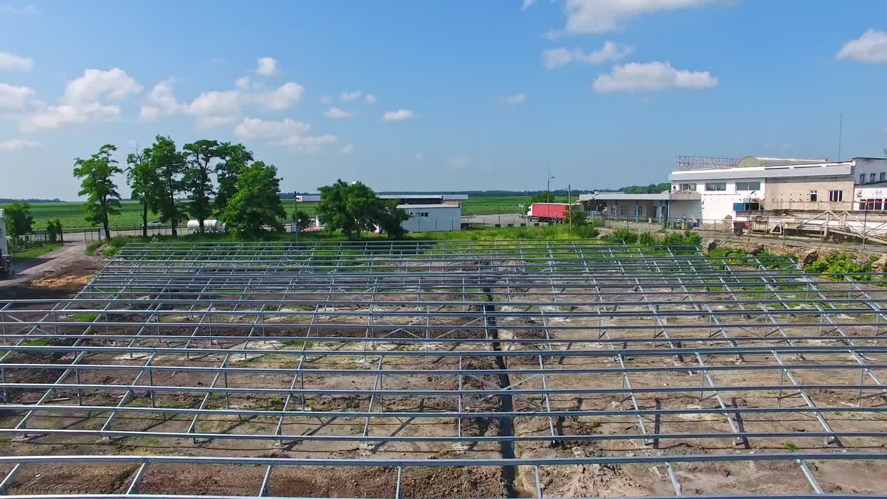 Field with metal construction for solar panels. Building of a new solar power plant among nature. Motion camera back.