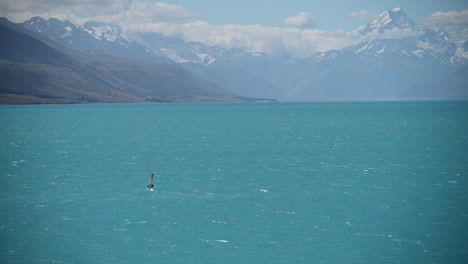 fast wind surfer on blue glacial lake with new zealand's highest mountain in background