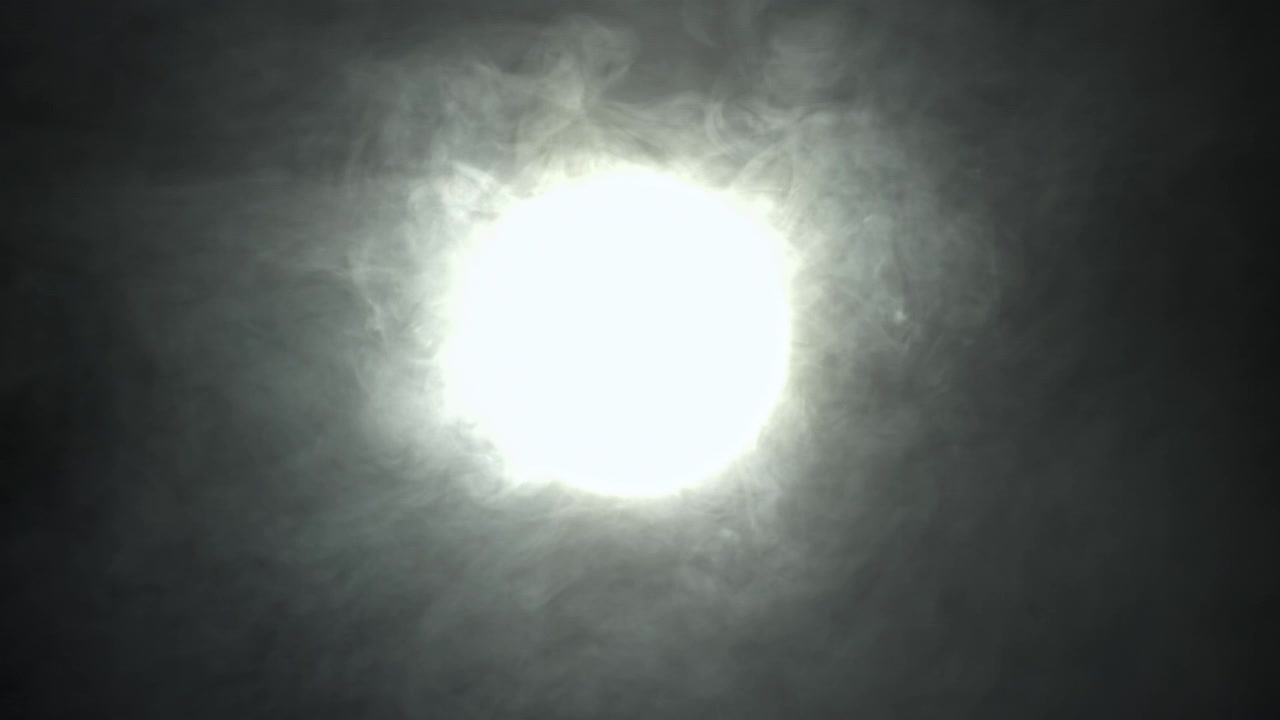 Sorgente luminosa intensa con fumo vorticoso su sfondo scuro