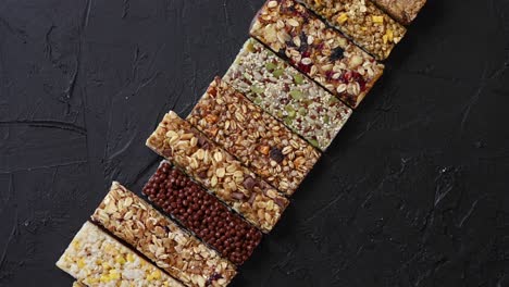 various healthy granola bars placed in a row on black stone table