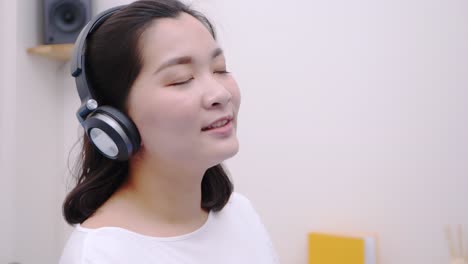 asian teenage woman using the bluetooth headphone for listening to streaming music so lovely lie in bed