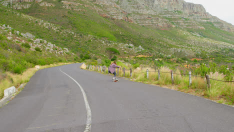 front view of stylish young woman doing skateboard trick on downhill at countryside road 4k