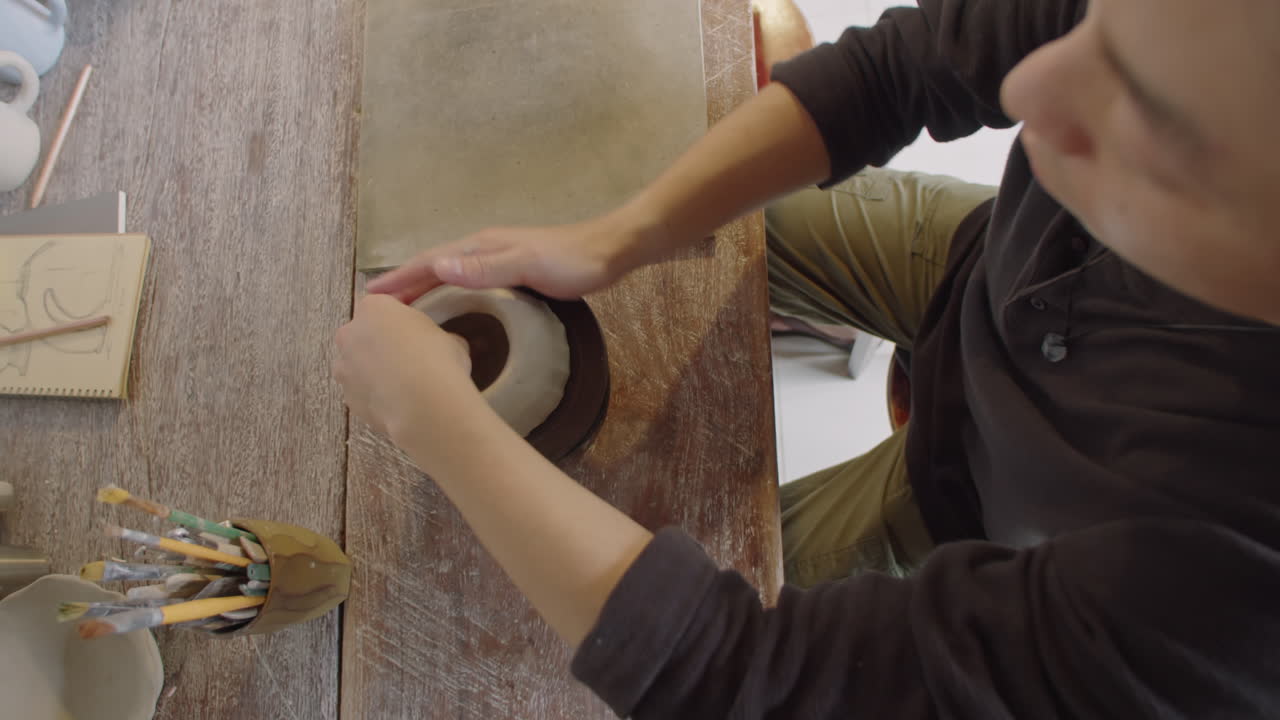 Ceramist Shaping Clay Vase on Pottery Wheel in Workshop
