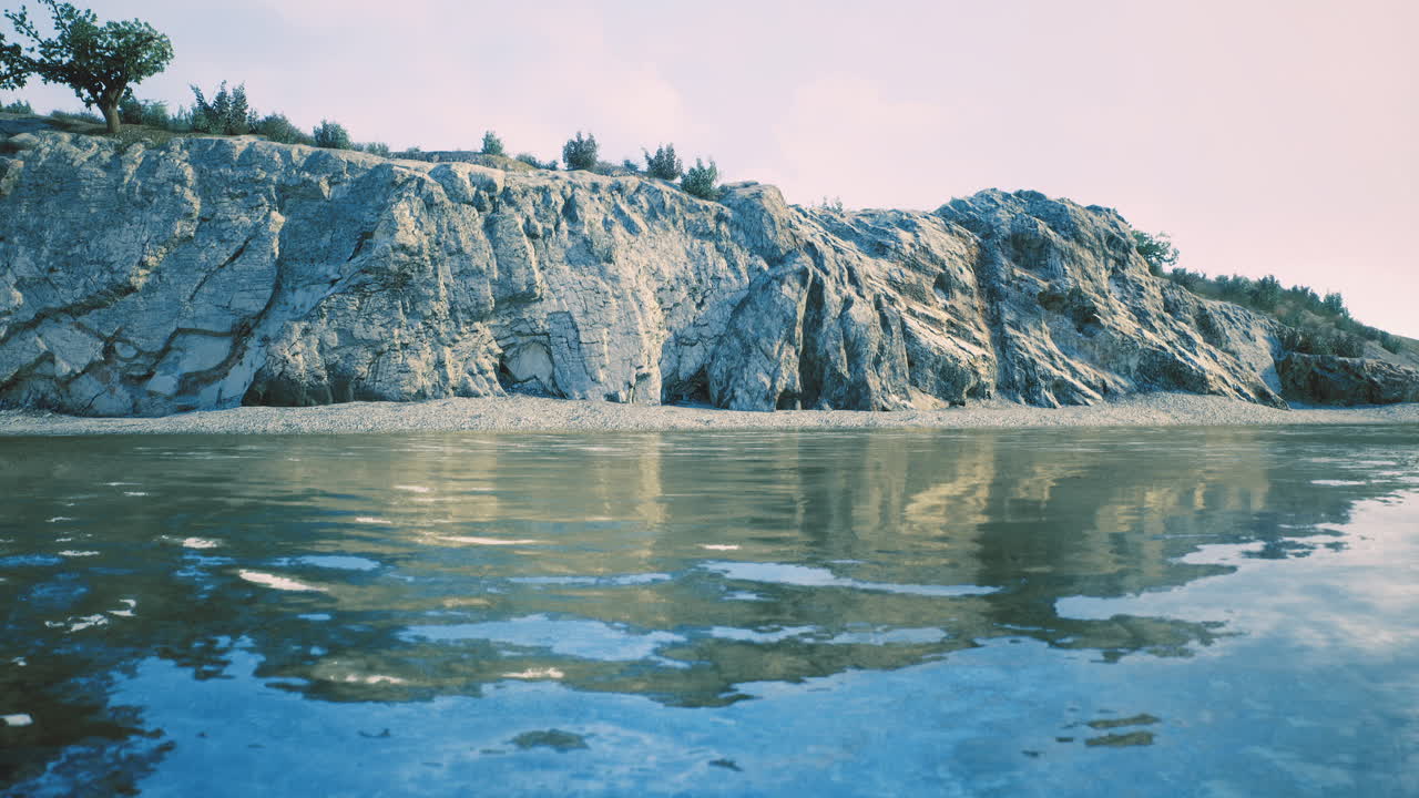 Serene shoreline with calm water reflecting rocky cliffs and greenery