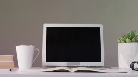 computadora portátil, libro abierto y taza de café