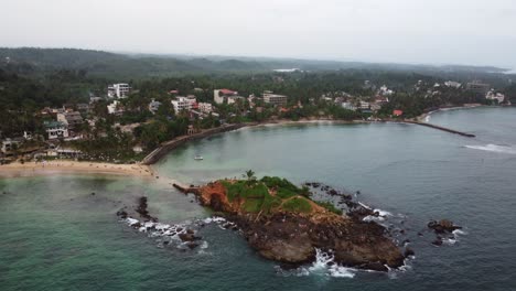 aerial drone panning above tropical rocky beaches and pigeon island coastline of tourist destination in sri lanka