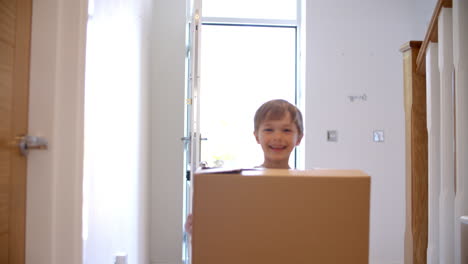 young boy carrying box into new home on moving day